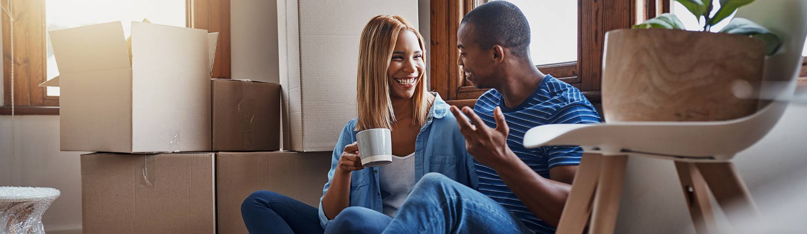 Young couple having coffee among boxes in their new home.