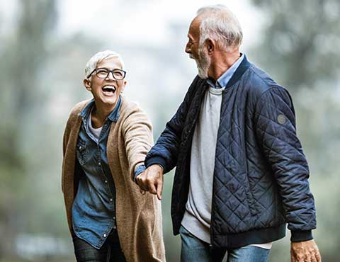 Retired couple holding hands walking.